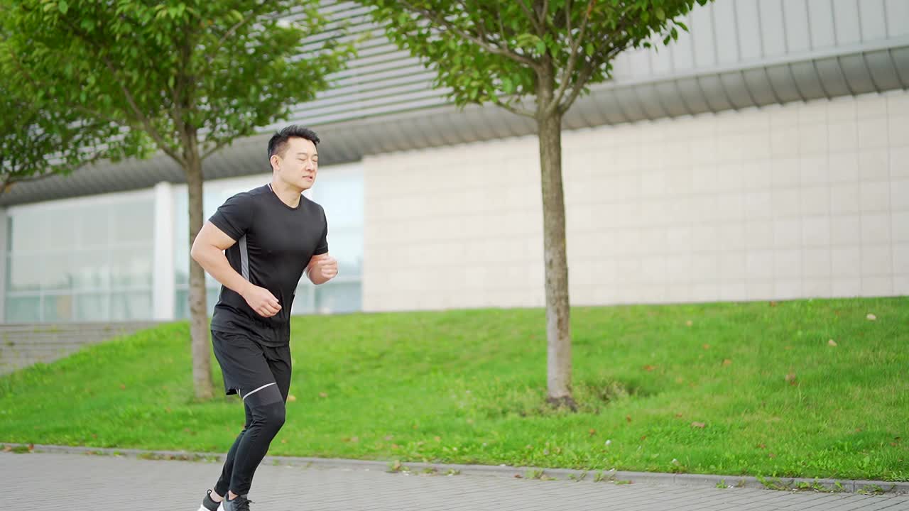 年轻的亚洲男子在城市和公园的街道上跑步，享受健身手表视频素材