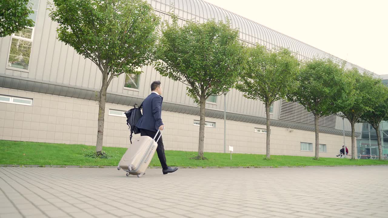 后视图亚洲旅游商人带着行李走过公共交通大楼的城市背景城市街道视频素材