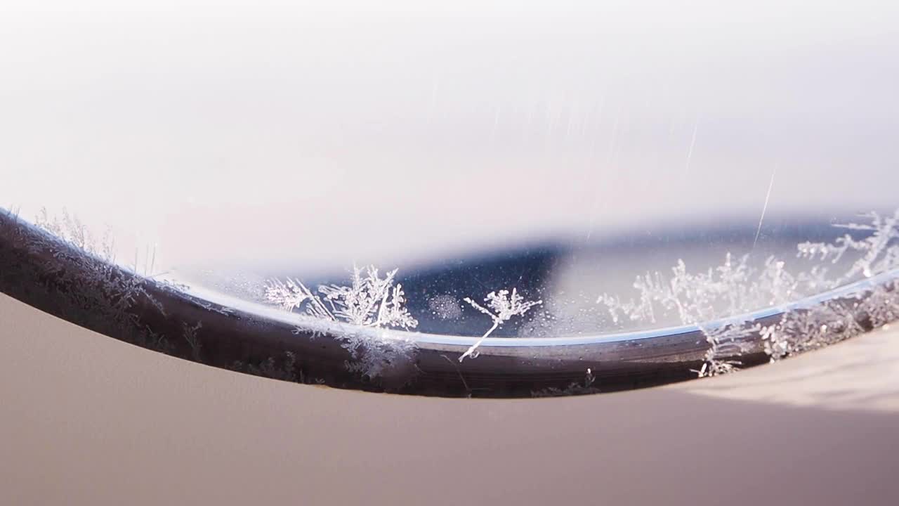 雪花落在飞机的窗户上。在云端安全飞行。窗外天冷，大气高。阳光照进飞机。美丽的雪花形状。冬季背景。视频素材