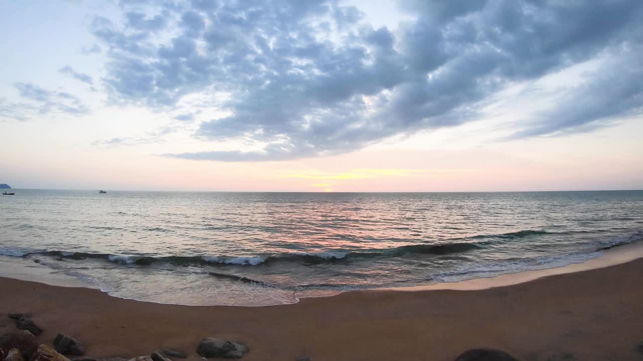 地平线上的日落。在傍晚的阳光下，海滩上的云朵和五彩缤纷的阳光。海水冲击着沙滩。阳光反射在水面上的红光。美丽的大海和海景视频素材