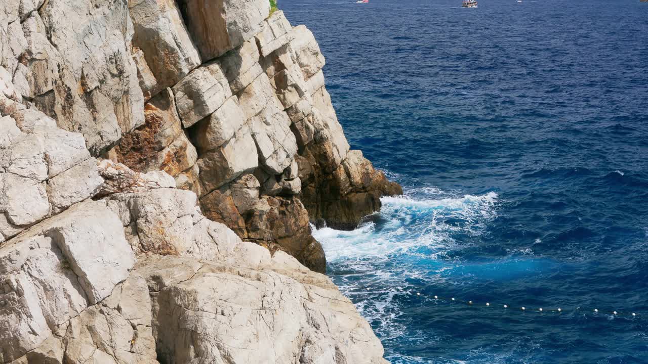 在一个阳光明媚的夏日，海浪拍打着岩石。视频素材