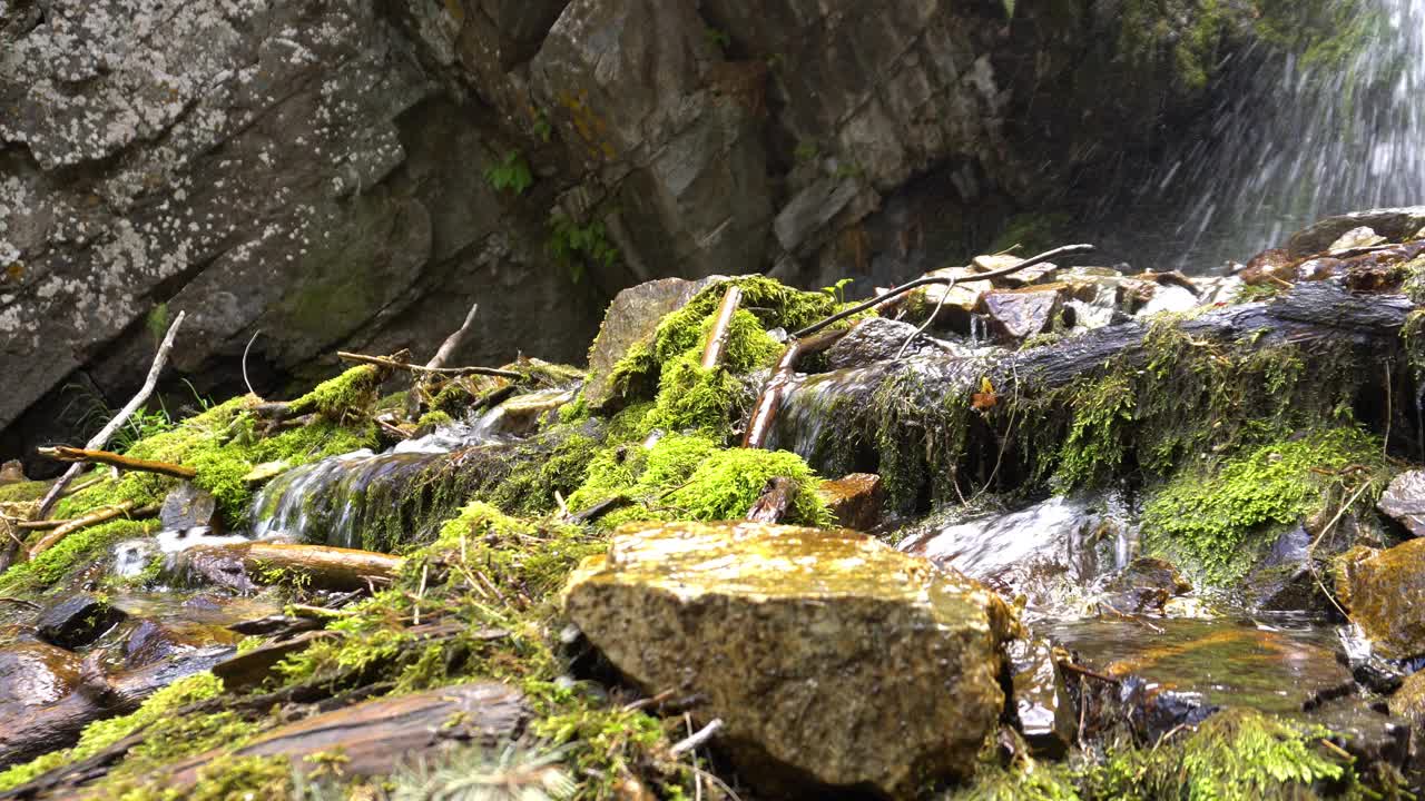 瀑布飞溅的水花落在岩石和圆木上视频素材