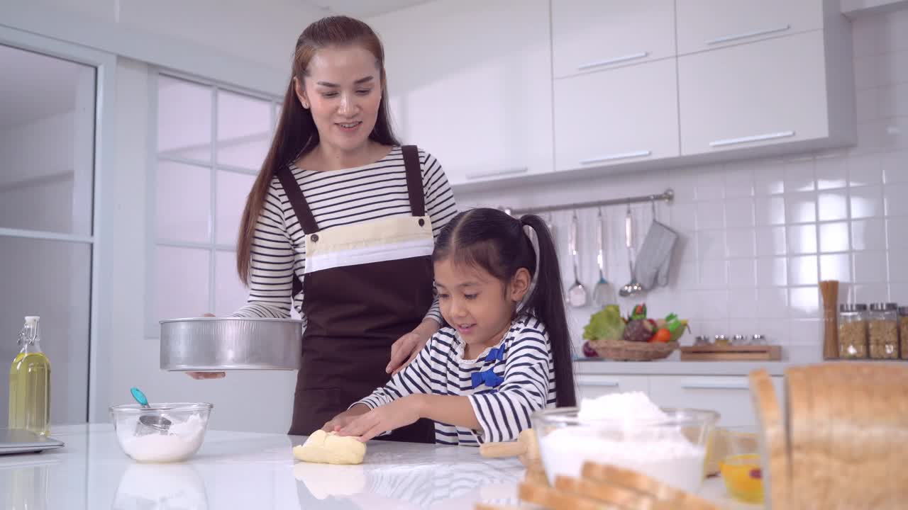 妈妈和孩子一起在家庭厨房做面团和烘焙，为家庭乐趣的概念。视频素材