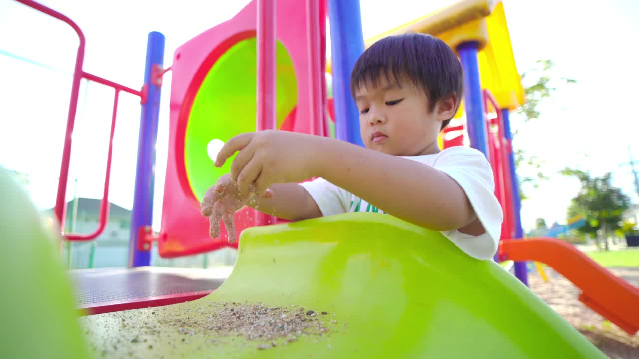 亚洲男孩在操场上玩耍，在夏天的阳光下视频素材