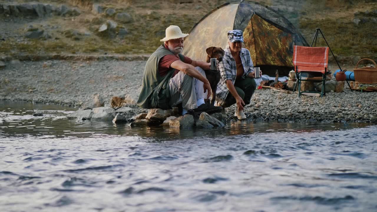 老夫妇一起在山溪的海滩上旅行，一起在河边喝热茶视频素材