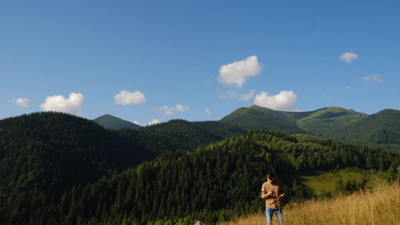 严肃的年轻人手持手机在背景山上寻找移动网络，游客迷路了。在自然城市外的互联网连接问题。不良信号通信概念视频素材