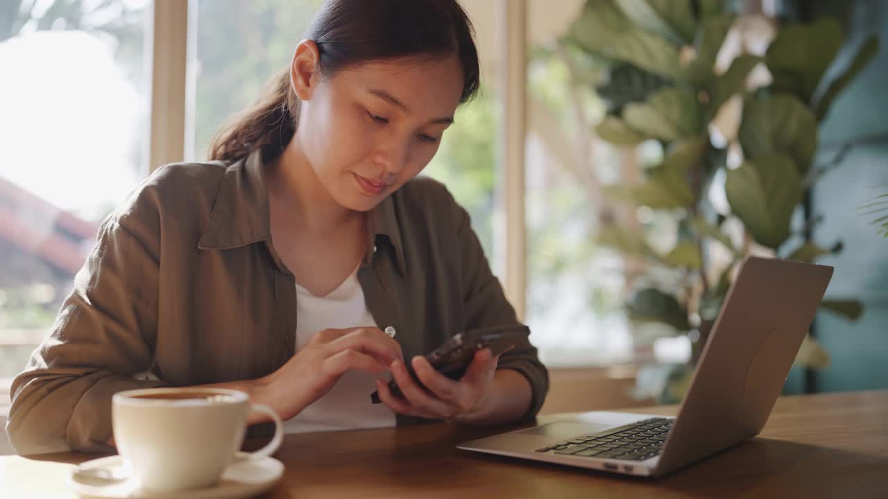 一个女人在咖啡店里用智能手机视频素材