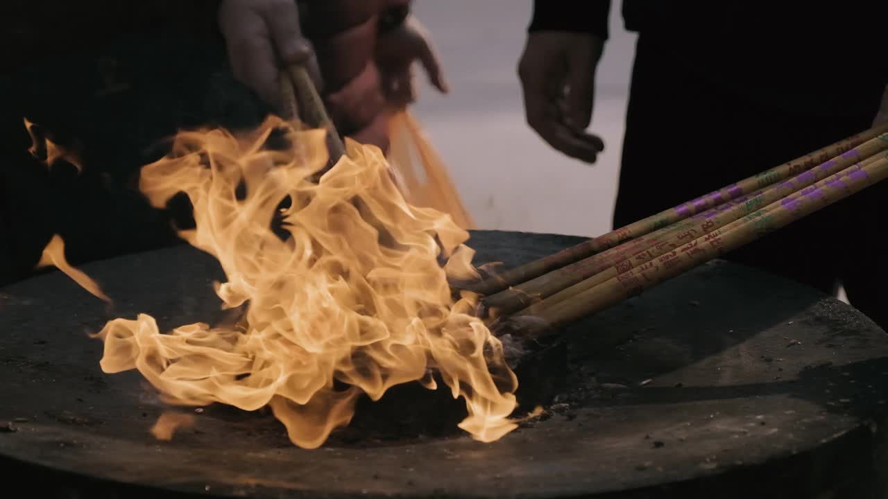 中国人在燃烧的壁炉上点香——慢动作视频素材