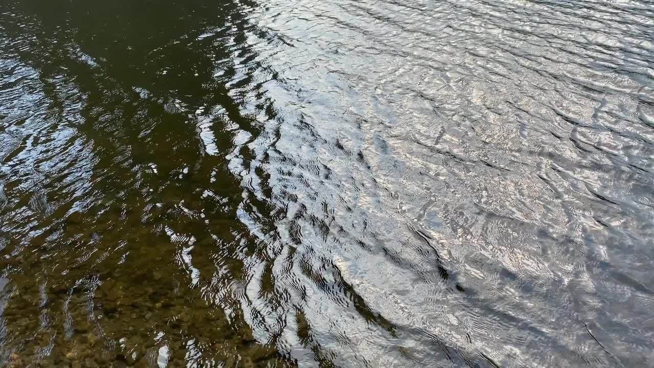 河水荡漾着波浪的背景。闪亮的黑暗湖水涟漪。视频素材