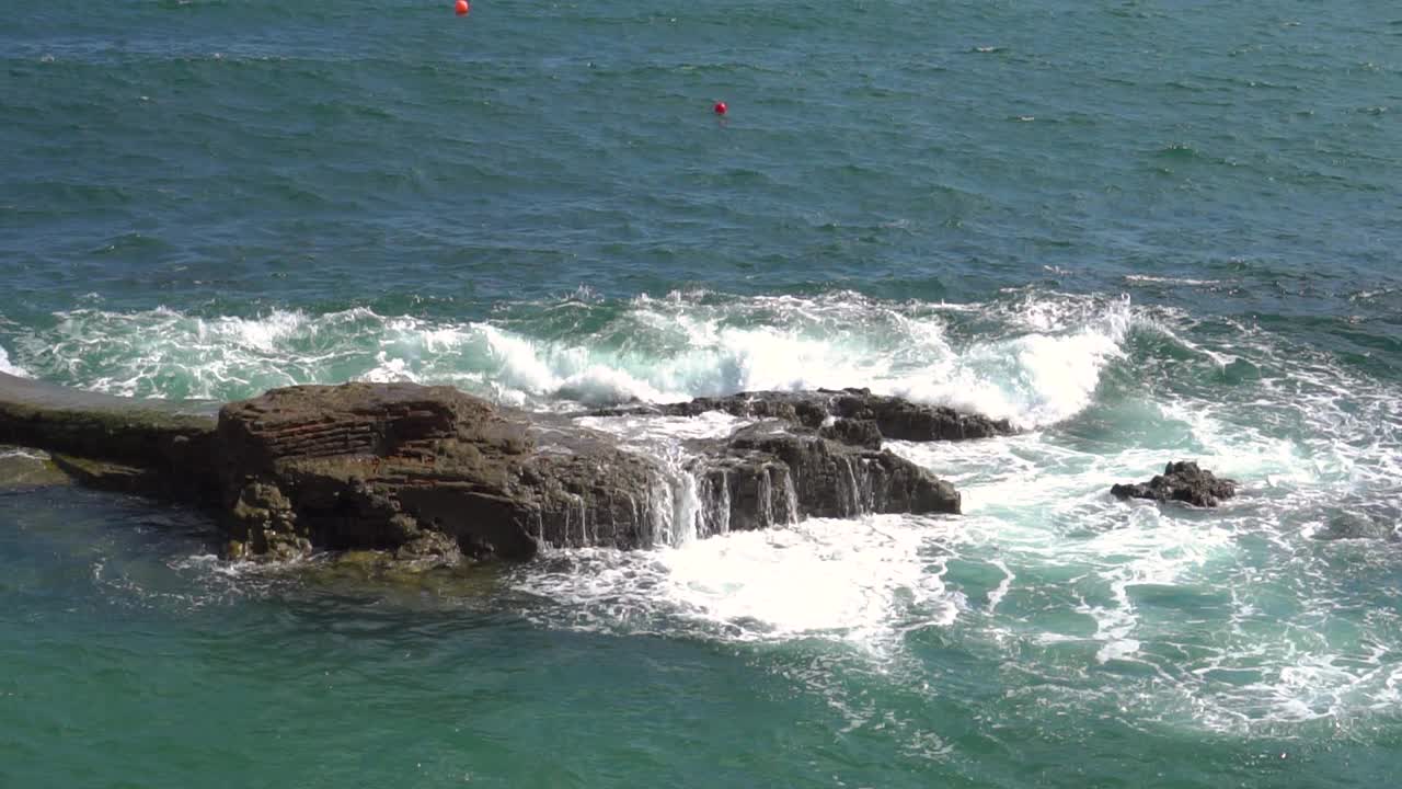 海浪拍打着海岸的石头，溅起水花视频素材