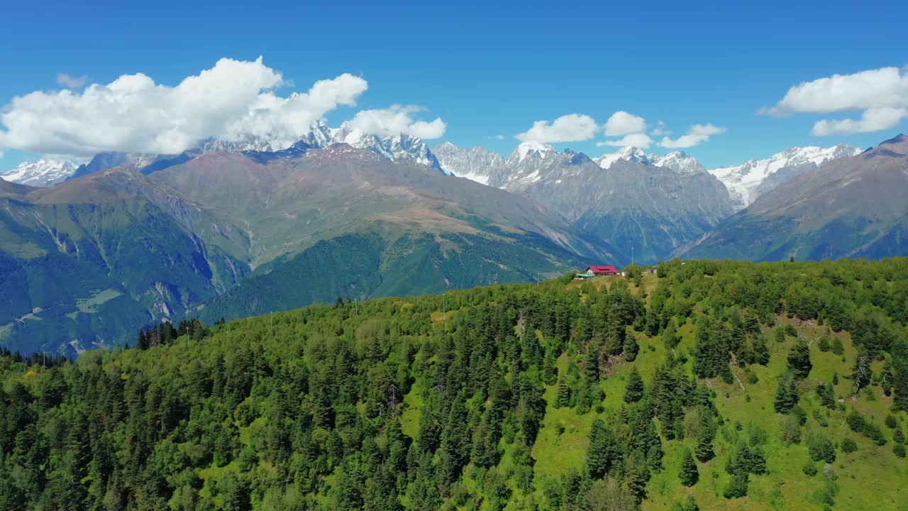 鸟瞰图，森林中的小房子在白雪皑皑的山峰的背景。视频素材