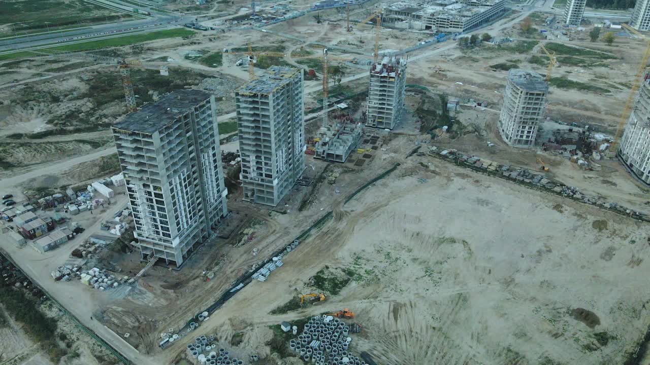 一个现代化城市街区的建筑工地。正在建设中的高层建筑。建筑塔式起重机。日落时的航空摄影。视频素材