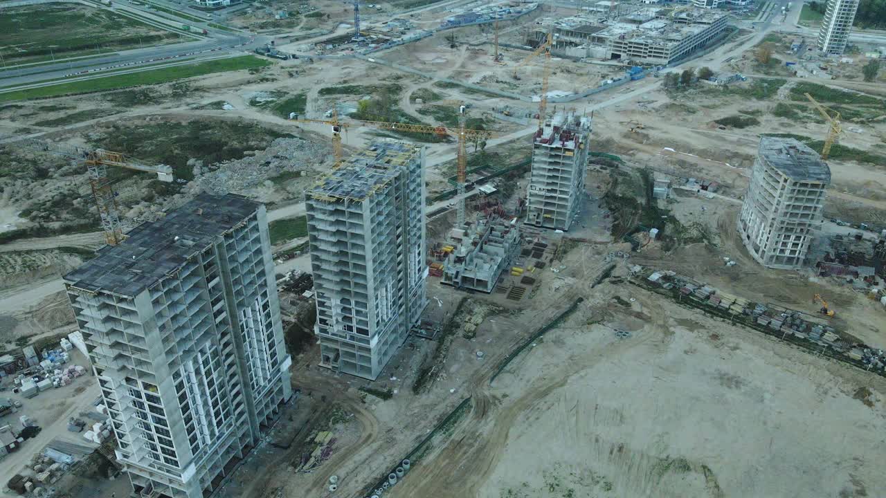 一个现代化城市街区的建筑工地。正在建设中的高层建筑。建筑塔式起重机。日落时的航空摄影。视频素材