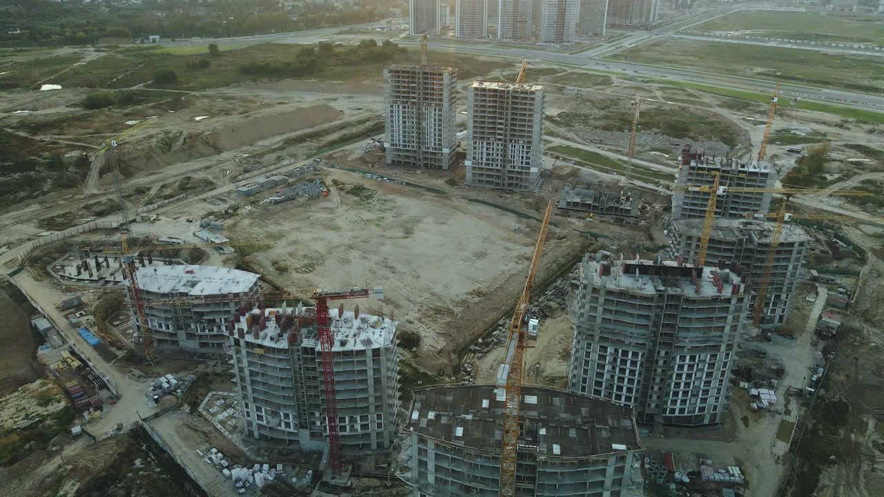 一个现代化城市街区的建筑工地。正在建设中的高层建筑。建筑塔式起重机。日落时的航空摄影。视频素材