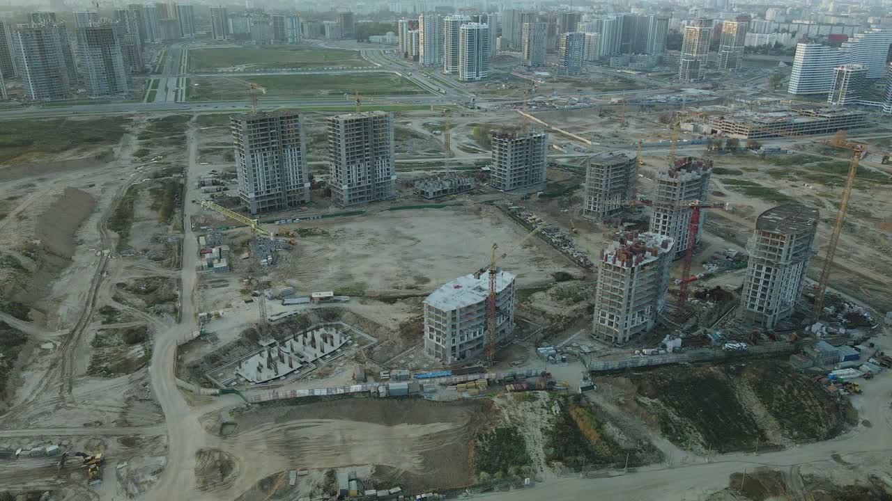 一个现代化城市街区的建筑工地。正在建设中的高层建筑。建筑塔式起重机。日落时的航空摄影。视频素材