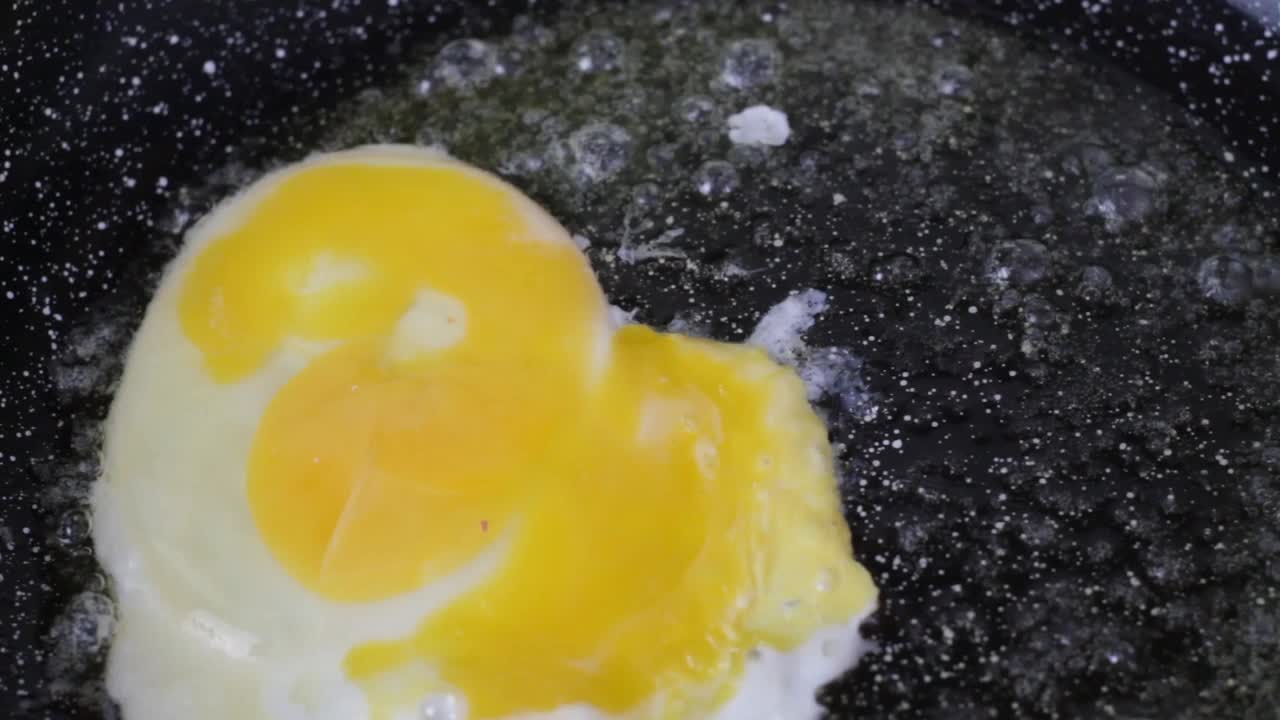 鸡蛋在热黄油煎锅里。俯视图视频下载