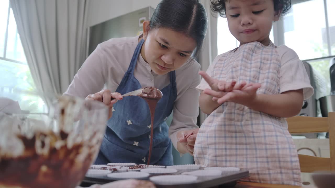 母亲和儿子一起做纸杯蛋糕。视频下载