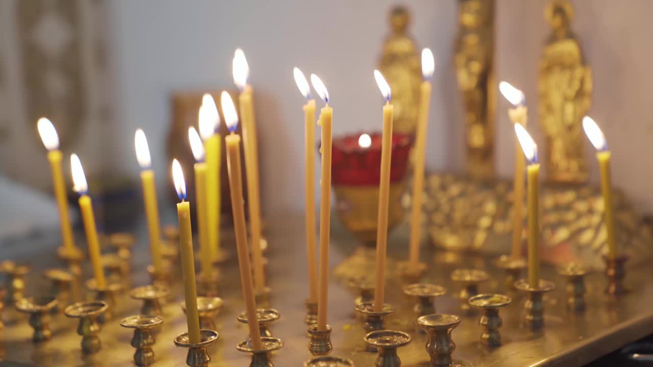 教堂里金色的烛台上燃烧着蜡烛。视频素材