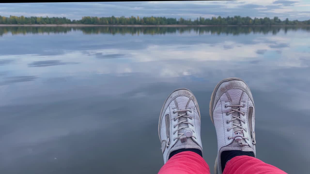 女人的腿穿着白色的窃笑和红色的裤子在蓝色的水中。旅游与旅游概念视频素材