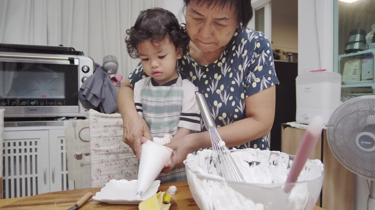 奶奶和孙子一起做甜点。视频素材