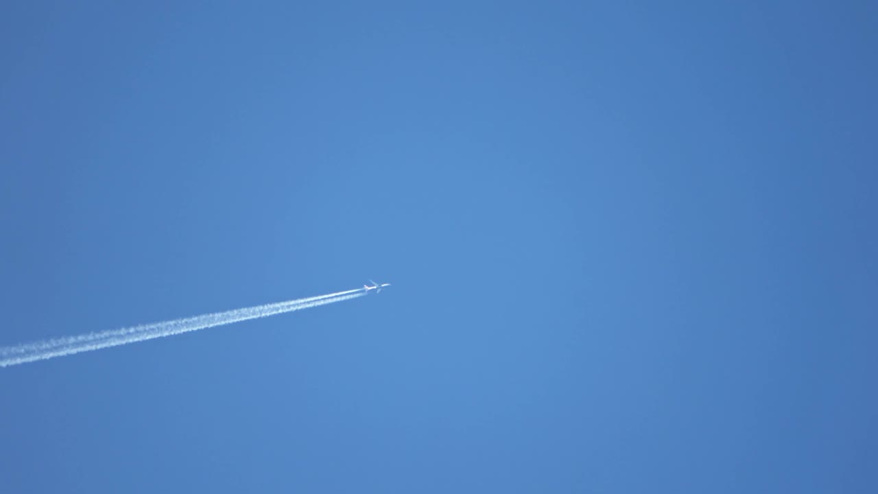 喷气式客机在高空飞行，在湛蓝的天空中留下了尾迹。视频素材