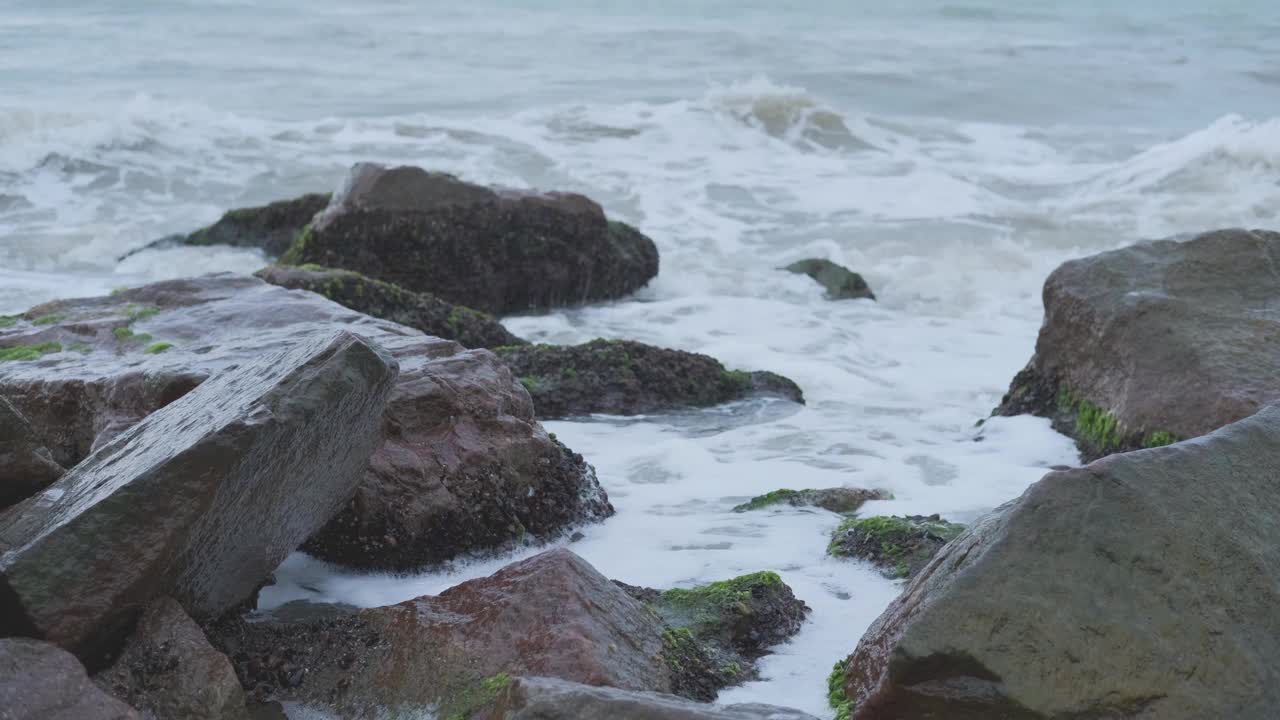 暴风雨中，带着泡沫的海浪拍打着岸边的石头视频素材