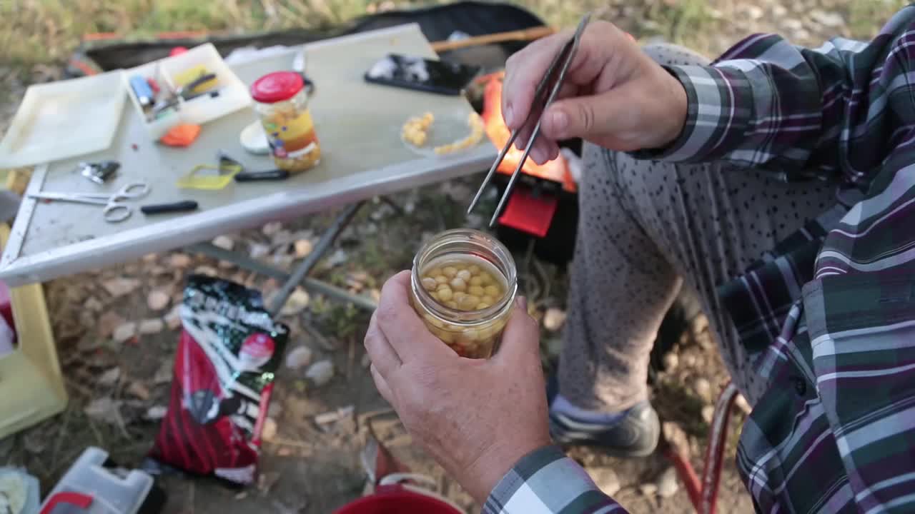 一位妇女正在挑选鱼饵玉米，准备挂在鱼钩上视频素材