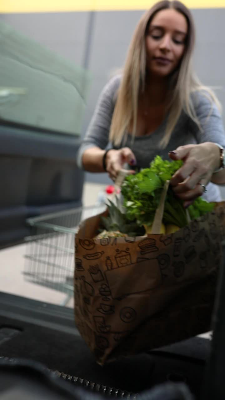 一个孕妇正在把食品杂货装进汽车后备箱视频素材