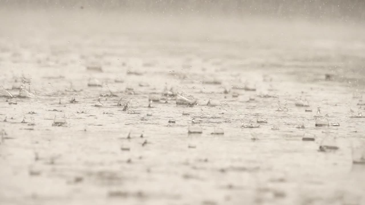 雨落在水泥地面上的水面上时，水滴形态的慢动作速度特写视频素材