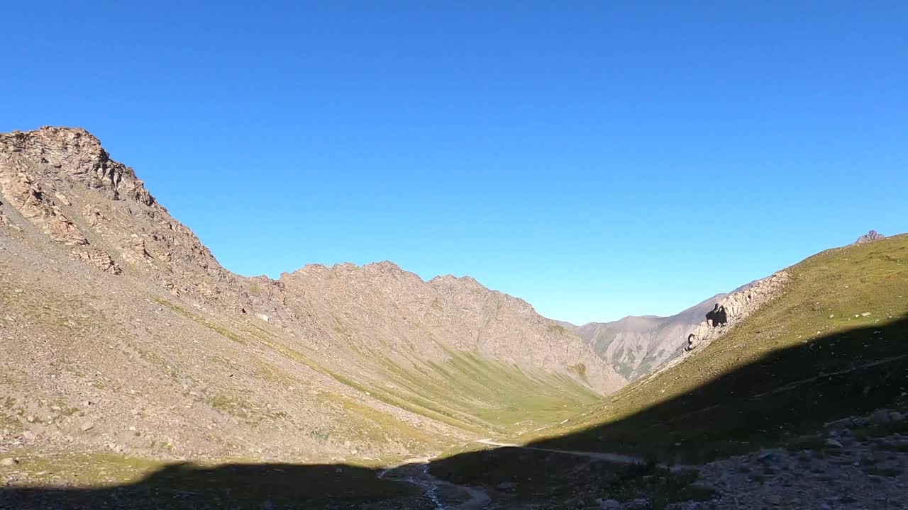 在意大利阿尔卑斯山脉的一条土路上，一辆行驶中的全地形车拍下了这段视频。你可以看到山谷，山谷里的路和上山的山坡上松动的石头。的客人视频素材