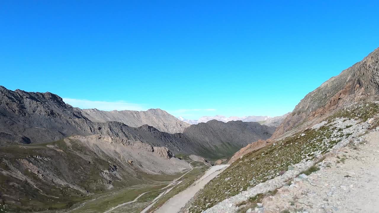 在意大利阿尔卑斯山脉的一条土路上，一辆行驶中的全地形车拍下了这段视频。你可以看到山谷，山谷里的路和上山的山坡上松动的石头。的客人视频素材