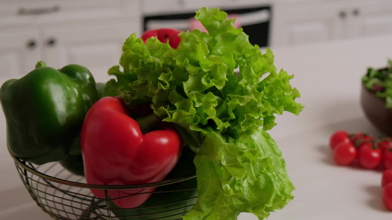 新鲜的蔬菜沙拉，红绿辣椒和圣女果放在桌子上，背景是白色的厨房视频素材