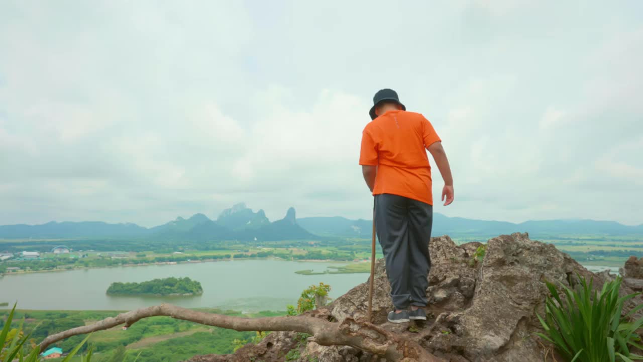 健康的亚洲男孩徒步上山，欣赏泰国岛上的风景，享受以山和树为背景的自然景观的和平和安静视频素材