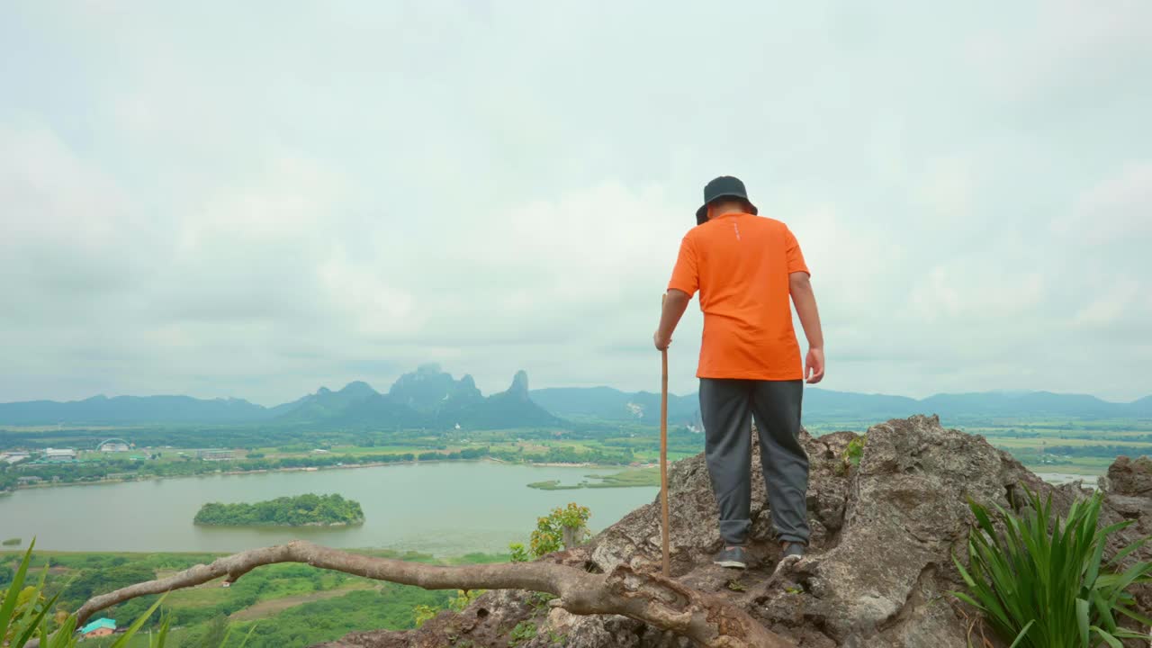 健康的亚洲男孩徒步上山，欣赏泰国岛上的风景，享受以山和树为背景的自然景观的和平和安静视频素材