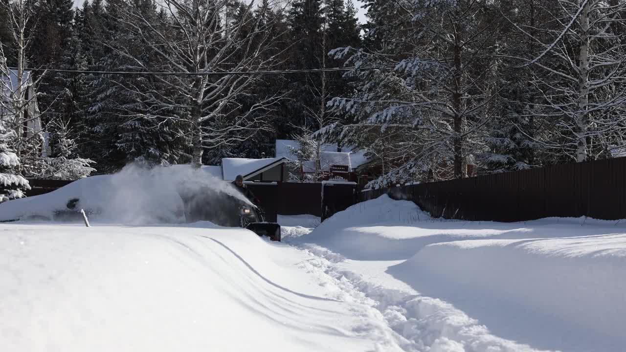 有人用吹雪机清扫人行道上的积雪。暴风雪过后，冬日阳光明媚的乡间小屋。视频素材