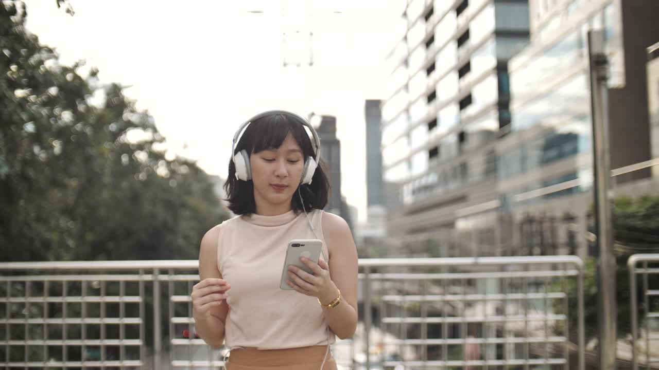 跳舞的亚洲女人用智能手机欣赏音乐视频素材