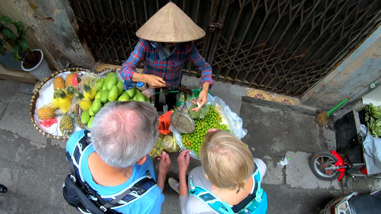 俯视河内市场一对老夫妇正在权衡李子视频素材