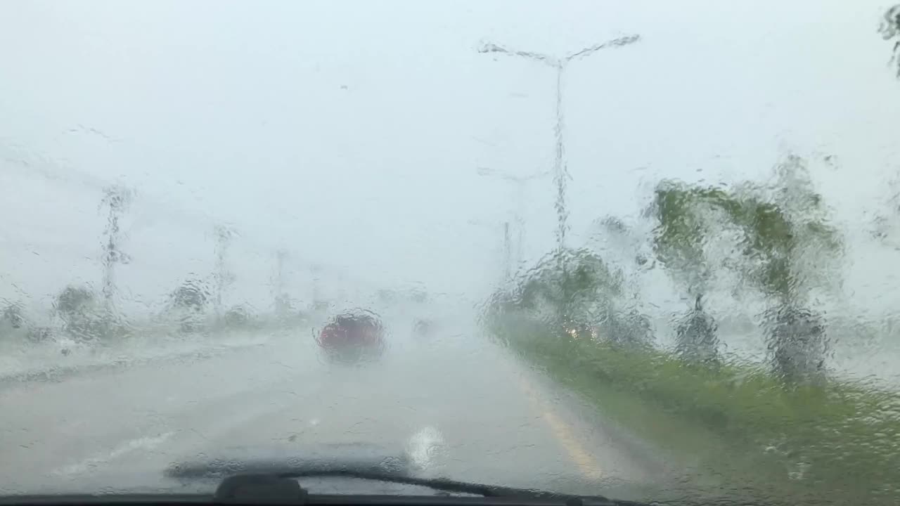 一辆车在大雨中行驶在路上。视频下载