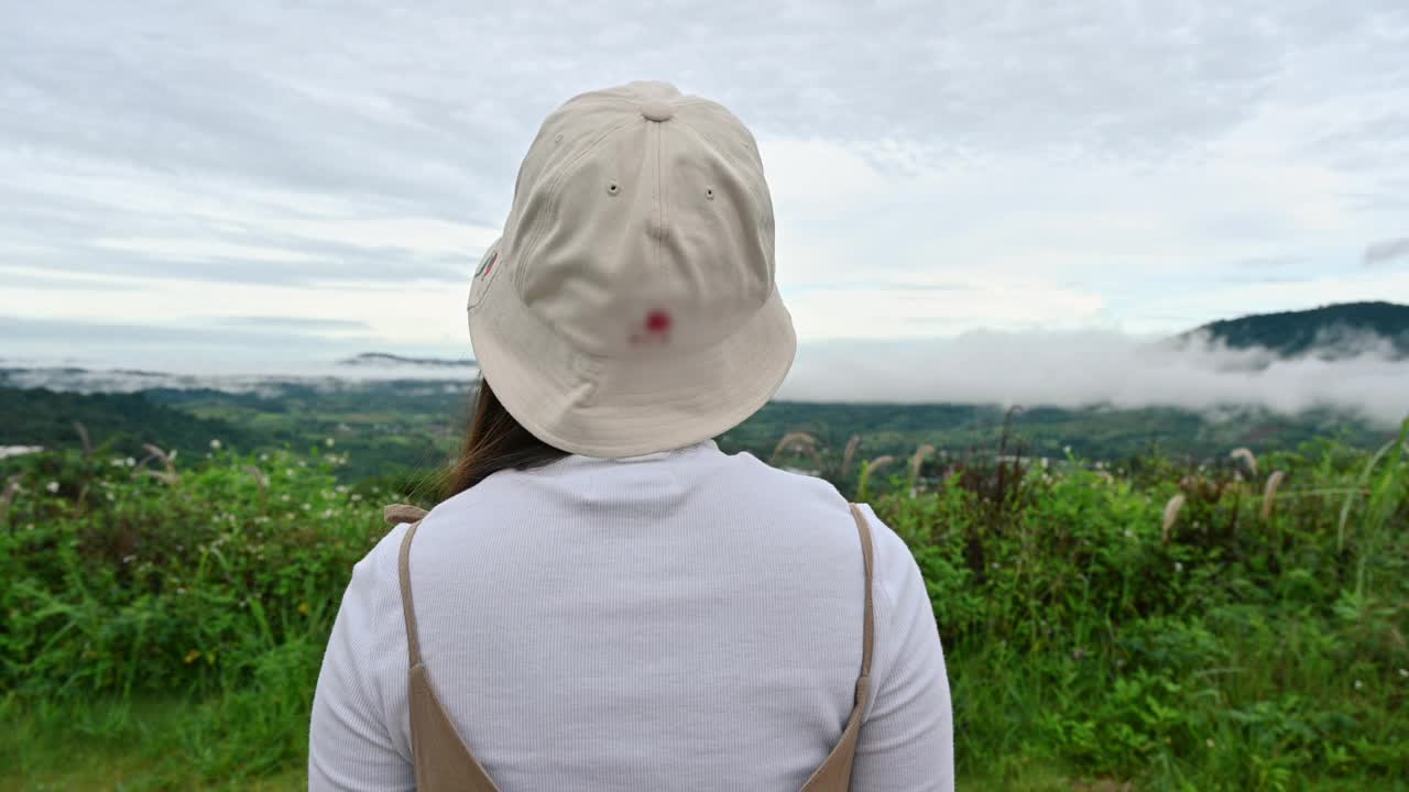 年轻的亚洲女人伸展手臂和看风景在山上的雾在假期视频素材