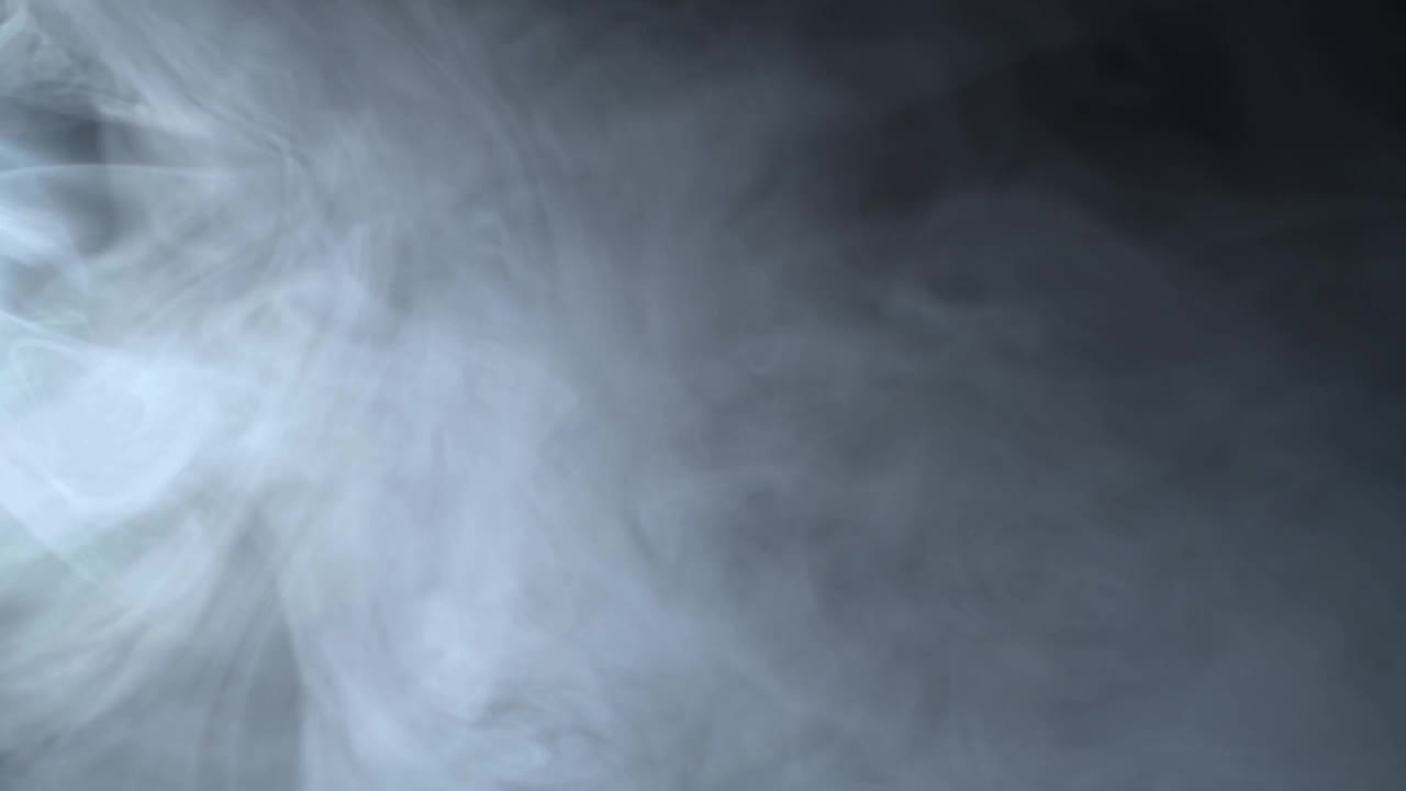 真实的烟雾云在一束手电筒在黑色背景。视频素材