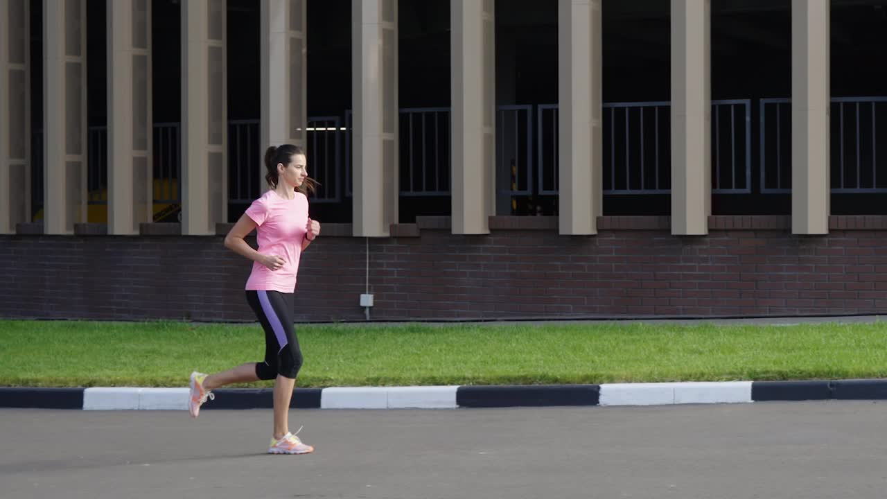 健美的女人以慢动作对着建筑物慢跑视频素材