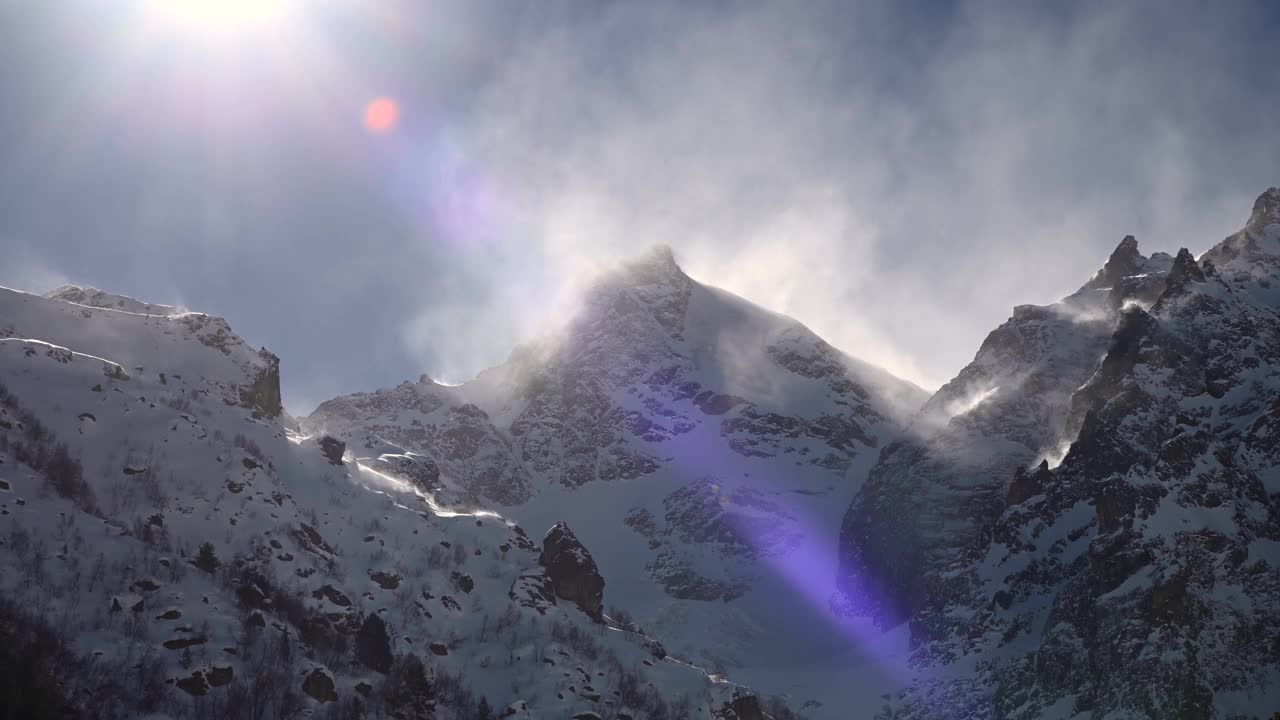 在长焦镜头上的时间流逝，高山的雪峰被风吹起的雪。山区恶劣的天气条件视频素材