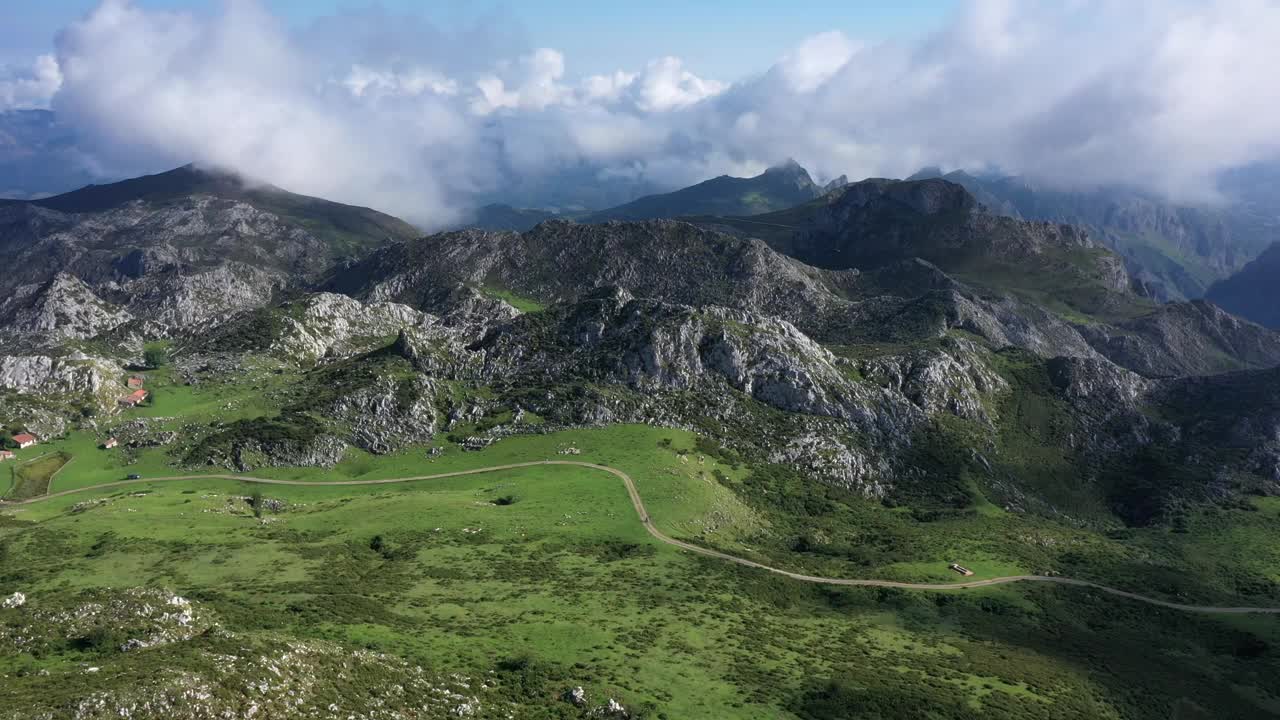 西班牙阿斯图里亚斯的拉戈斯德科瓦东加(Lagos de Covadonga)附近，阳光明媚的夏日，皮科斯德欧罗巴国家公园(Picos de Europa National Park)，俯瞰道路、绿色草地和岩石山脉的鸟瞰图视频素材