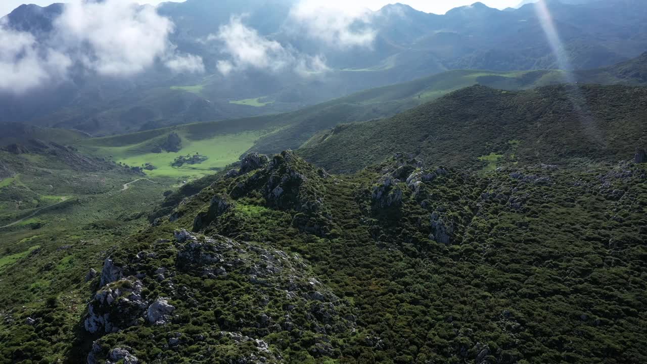 鸟瞰山谷和道路，在绿色的山脉和低云之间，在欧洲国家公园的山峰，阳光明媚的夏天，在西班牙阿斯图里亚斯-跟踪，pan shot视频素材