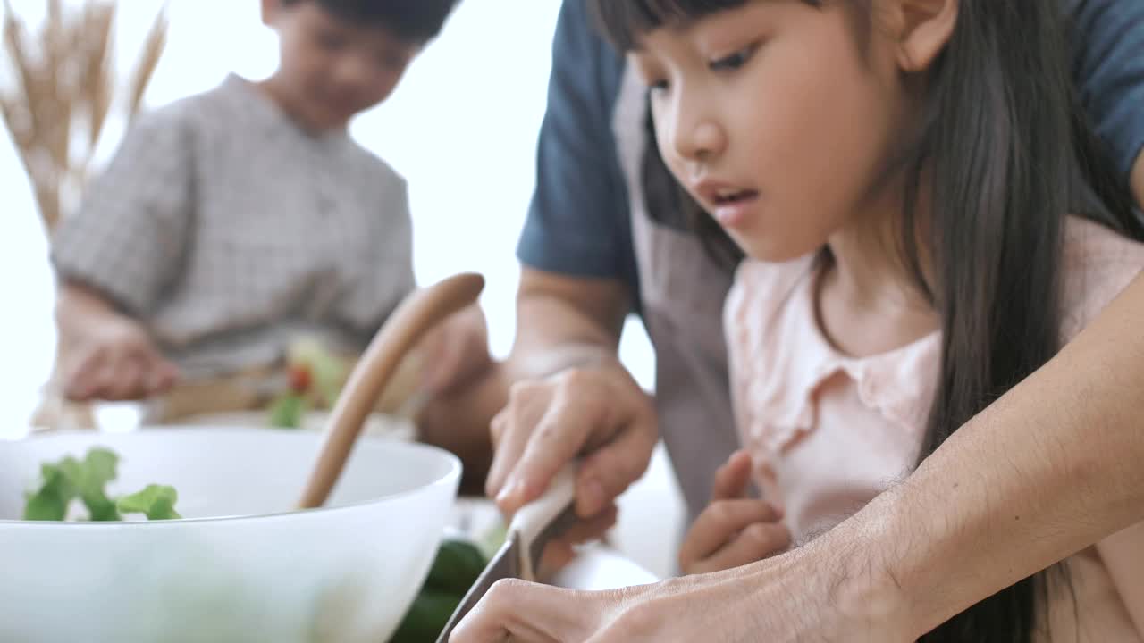 父亲、女儿和儿子在家里的厨房里做蔬菜沙拉。视频素材