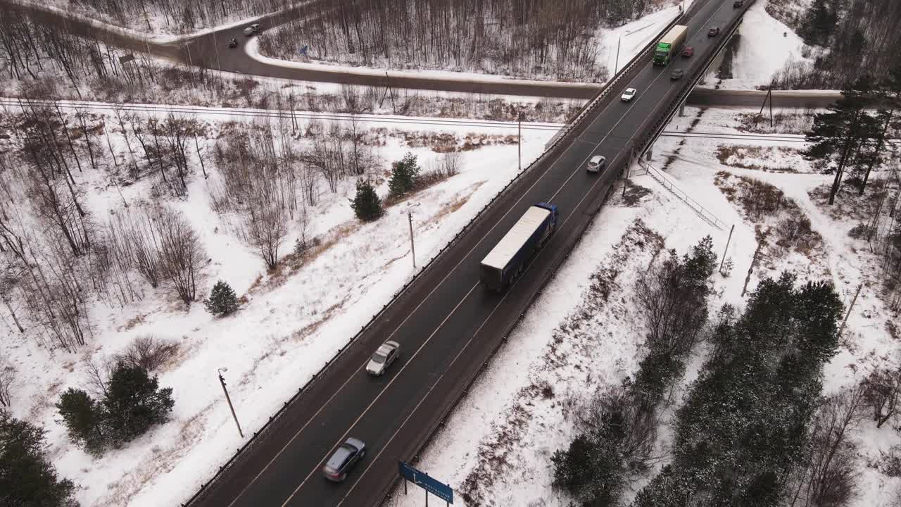 公路上的卡车和汽车在冬天的桥上行驶，鸟瞰图。视频素材