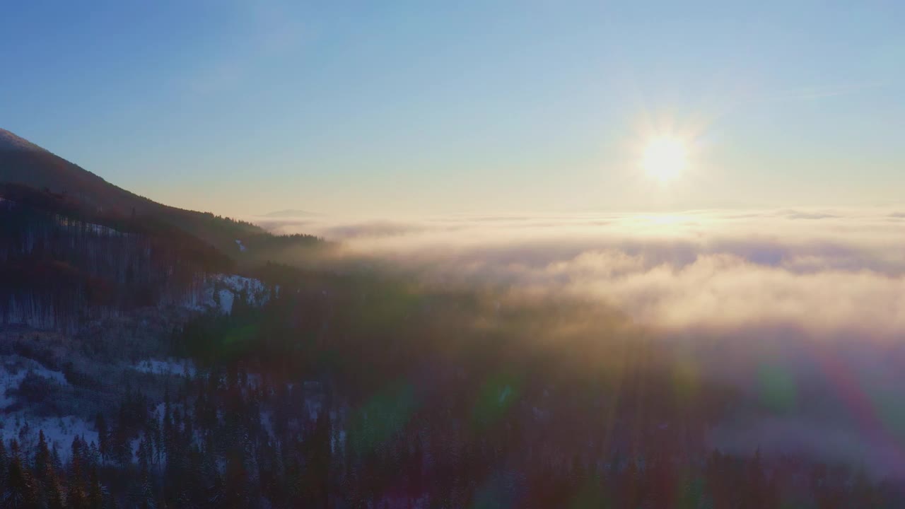 雾蒙蒙的山谷覆盖着白雪覆盖的山脉和绿色的森林视频素材