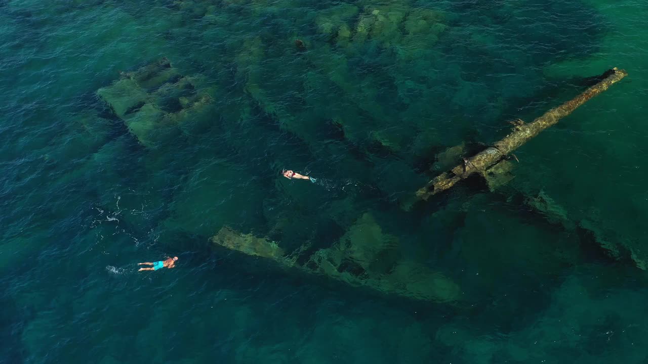 从上面看，令人惊叹的鸟瞰图，一些人游泳和浮潜周围的克里斯索沉船躺在海底。视频素材