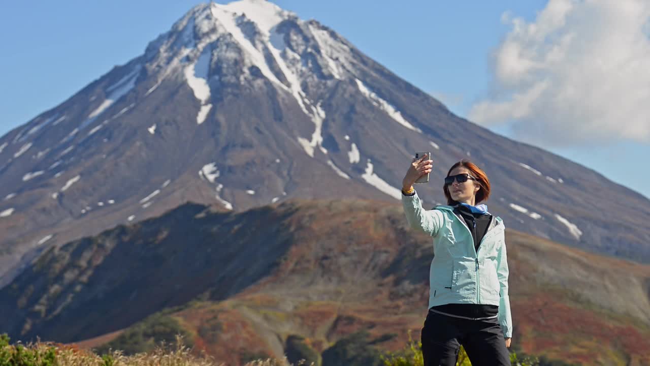 秋天，一名女子站在堪察加半岛山脉的背景下自拍视频素材