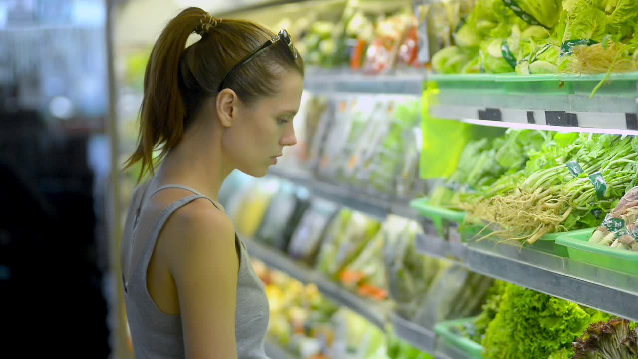 美国素食女孩选择新鲜的绿色沙拉站在有机商店视频素材